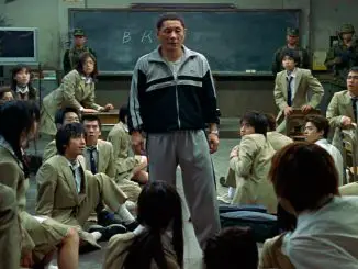 Battle Royale: Der ehemalige Lehrer Kitano (Takeshi Kitano) erklärt den Schüler/innen, dass sie von nun an gegeneinander ums Überleben kämpfen